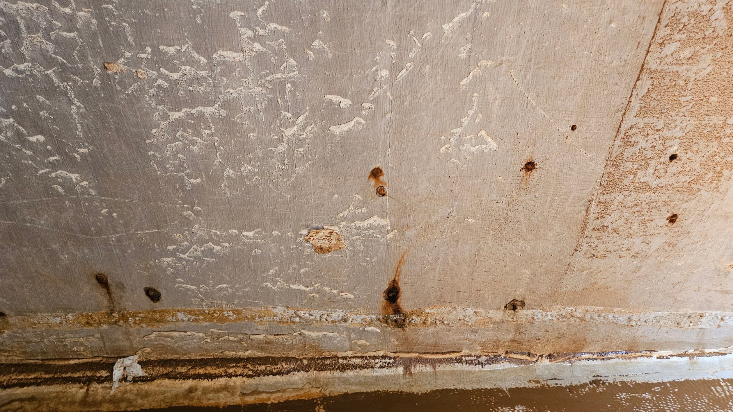 Muro de concreto con puntos de corrosión y acero expuesto tras retirar un recubrimiento fallado